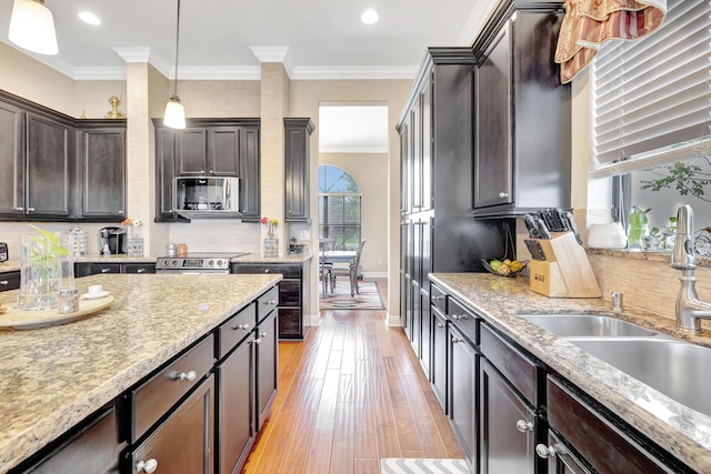 kitchen featuring decorative light fixtures, light hardwood / wood-style floors, dark brown cabinets, and sink