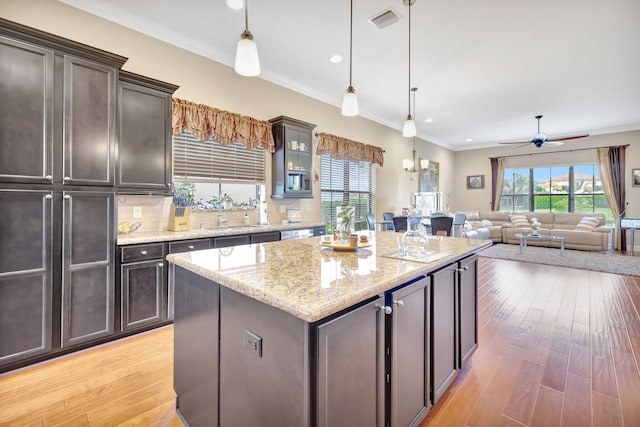 kitchen with a center island, light hardwood / wood-style flooring, hanging light fixtures, and ornamental molding