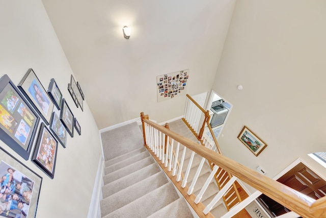 stairway featuring a towering ceiling and carpet floors