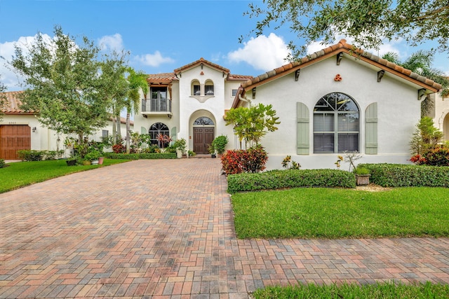 mediterranean / spanish house featuring a balcony and a front yard