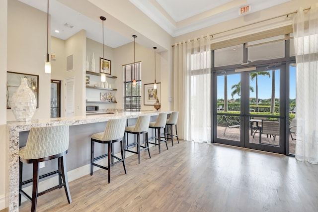 kitchen featuring kitchen peninsula, pendant lighting, light hardwood / wood-style flooring, and a breakfast bar area