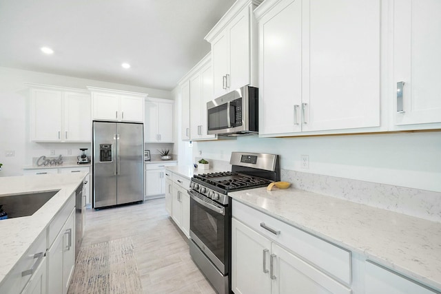 kitchen featuring white cabinets, appliances with stainless steel finishes, and light stone counters