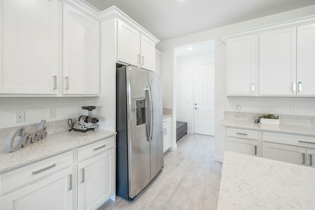 kitchen featuring white cabinets, stainless steel fridge with ice dispenser, light hardwood / wood-style flooring, and light stone counters