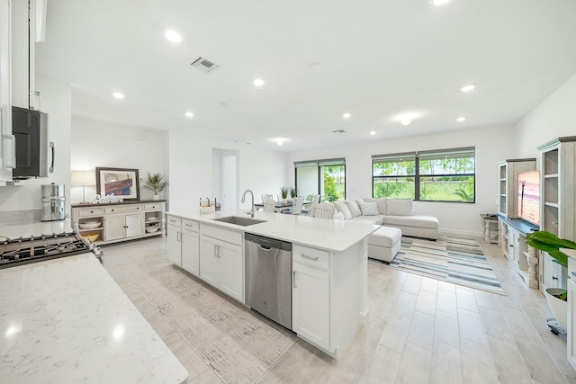 kitchen featuring light stone countertops, appliances with stainless steel finishes, sink, light hardwood / wood-style flooring, and white cabinetry