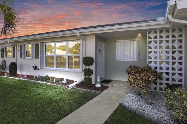 exterior entry at dusk featuring a yard