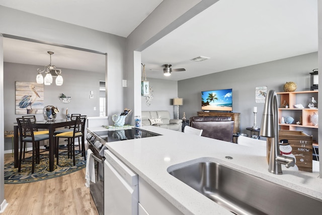 kitchen featuring white appliances, ceiling fan with notable chandelier, sink, hanging light fixtures, and light hardwood / wood-style floors