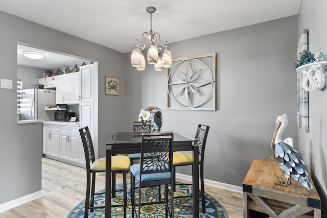 dining area with light hardwood / wood-style flooring and a chandelier