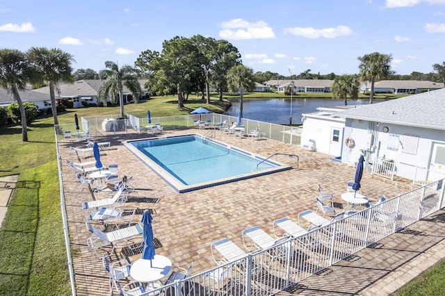 view of pool featuring a lawn, a water view, and a patio