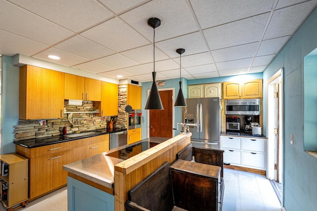 kitchen with sink, a drop ceiling, backsplash, a kitchen island, and appliances with stainless steel finishes