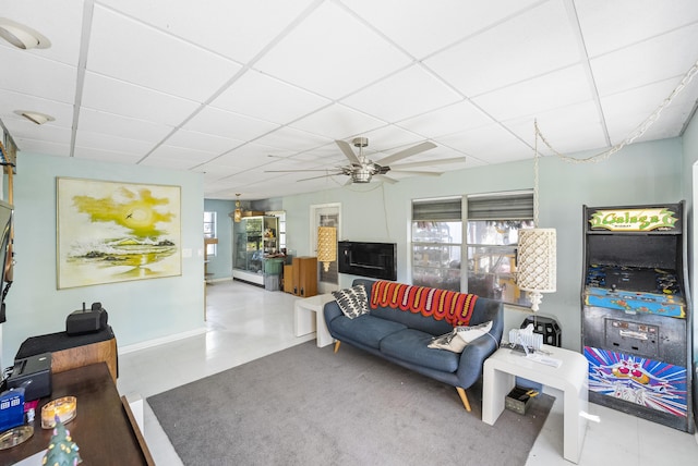 living room with a drop ceiling, ceiling fan, and plenty of natural light