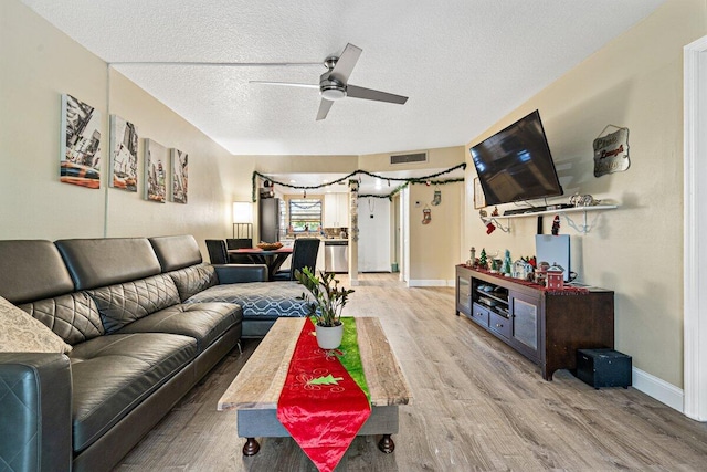 living room with ceiling fan, wood-type flooring, and a textured ceiling