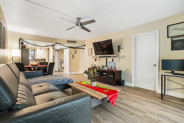 living room with ceiling fan, hardwood / wood-style floors, and a textured ceiling