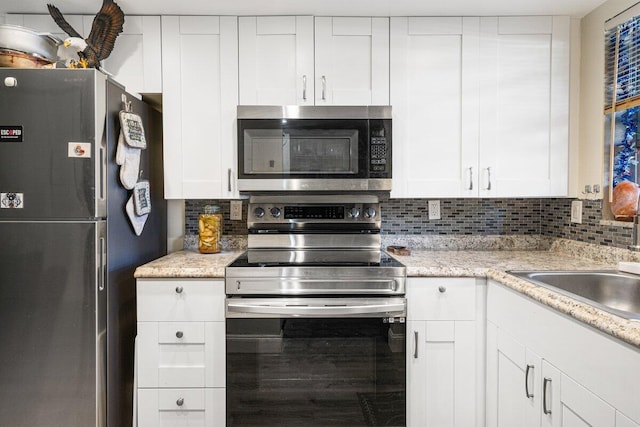 kitchen with white cabinets, appliances with stainless steel finishes, and backsplash