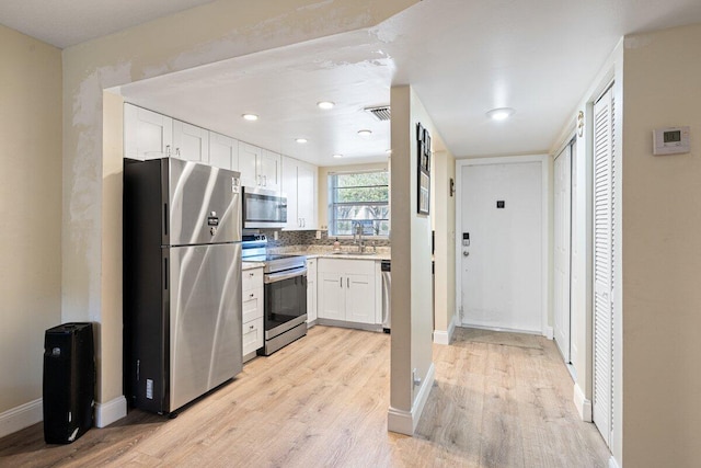 1638 Embassy Dr Unit 103, West Palm Beach, FL 33401 - kitchen featuring a sink, light wood-style flooring, white cabinets, appliances with stainless steel finishes, and visible vents