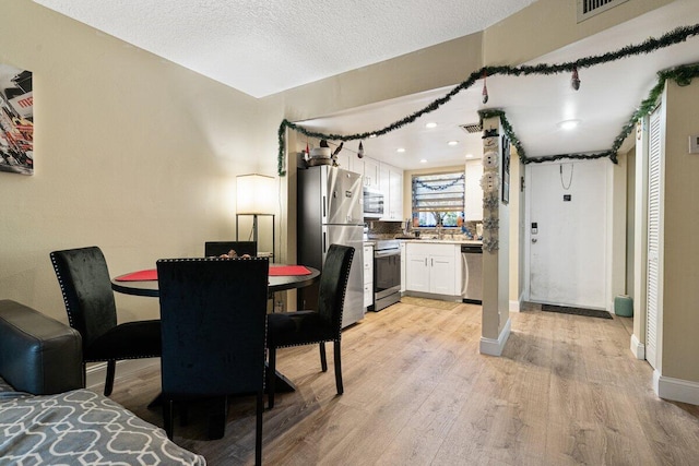 dining room featuring a textured ceiling and light hardwood / wood-style flooring