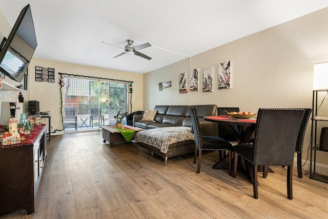 living room with ceiling fan, light hardwood / wood-style floors, and a textured ceiling