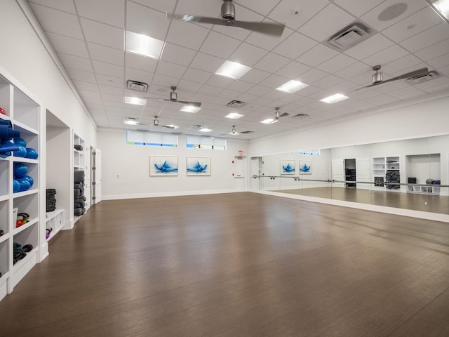 workout area with ceiling fan, a drop ceiling, and hardwood / wood-style flooring