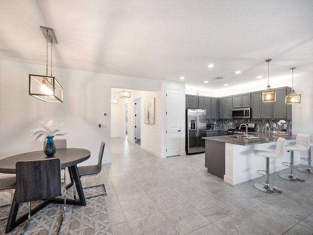 kitchen featuring tasteful backsplash, hanging light fixtures, stainless steel appliances, and sink