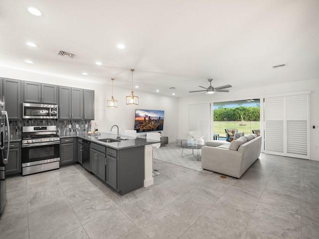 kitchen featuring dark stone counters, sink, gray cabinets, kitchen peninsula, and stainless steel appliances