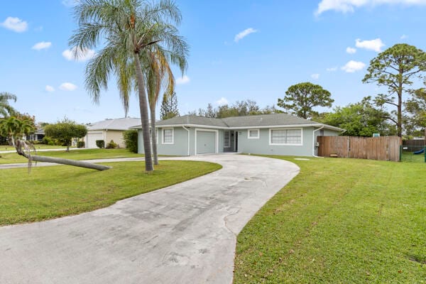 ranch-style house featuring a garage and a front lawn