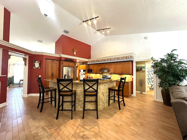 kitchen with a kitchen breakfast bar, light wood-type flooring, stainless steel appliances, and rail lighting