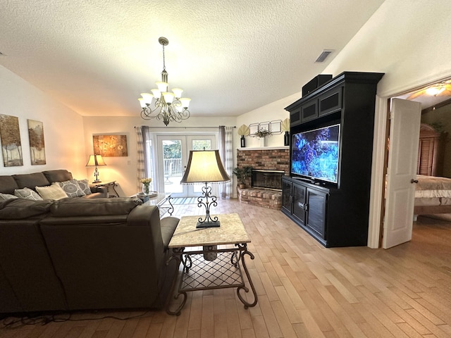 17976 88th Rd N, Loxahatchee, FL 33470 - living room featuring a chandelier, light wood finished floors, a textured ceiling, and a brick fireplace