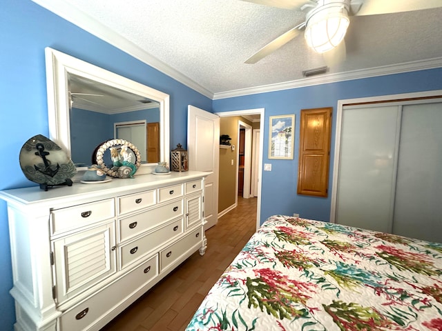 bedroom with dark wood-type flooring, crown molding, ceiling fan, a textured ceiling, and a closet