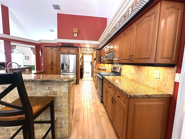 kitchen featuring a kitchen breakfast bar, crown molding, stone countertops, decorative backsplash, and appliances with stainless steel finishes