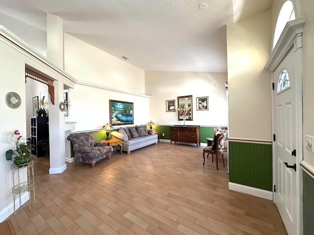 living room with high vaulted ceiling, light hardwood / wood-style floors, and a textured ceiling