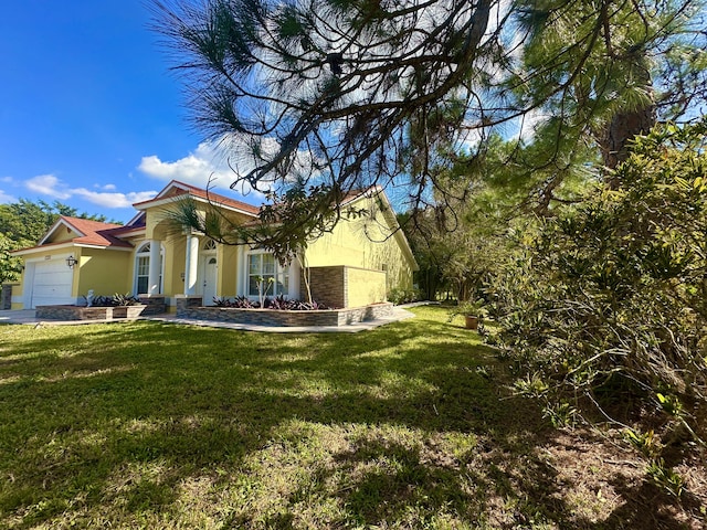 17976 88th Rd N, Loxahatchee, FL 33470 - view of side of property featuring stucco siding, a lawn, a garage, and stone siding