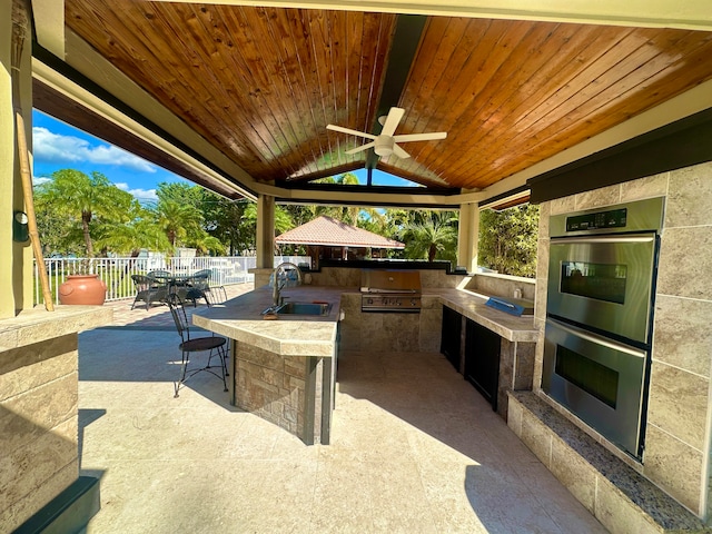 view of patio / terrace featuring a gazebo, ceiling fan, area for grilling, and a wet bar