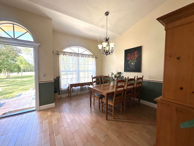 dining area with hardwood / wood-style floors, a healthy amount of sunlight, a textured ceiling, and an inviting chandelier