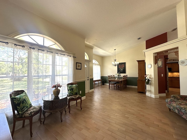 17976 88th Rd N, Loxahatchee, FL 33470 - living area with a chandelier, a textured ceiling, vaulted ceiling, baseboards, and wood finished floors
