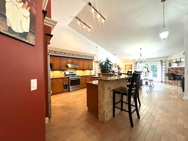 kitchen featuring a kitchen breakfast bar, a brick fireplace, gas range, a chandelier, and hanging light fixtures