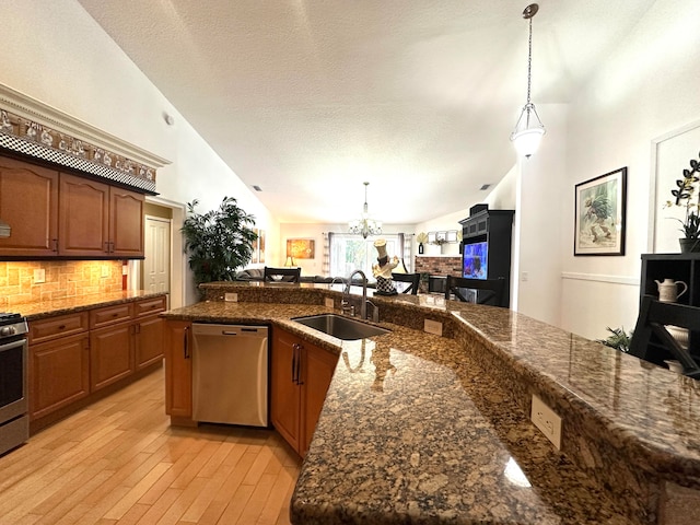 kitchen featuring sink, stainless steel appliances, decorative light fixtures, and light hardwood / wood-style flooring