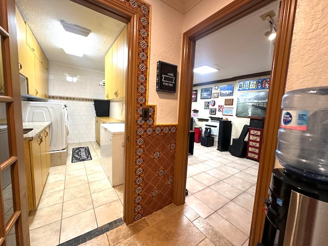 bathroom with ornamental molding, a textured ceiling, tile walls, tile patterned flooring, and independent washer and dryer