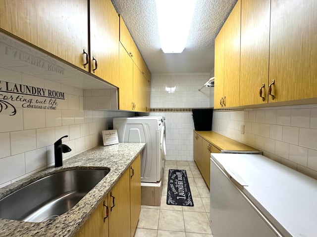 kitchen featuring sink, washer and dryer, light tile patterned floors, a textured ceiling, and tasteful backsplash