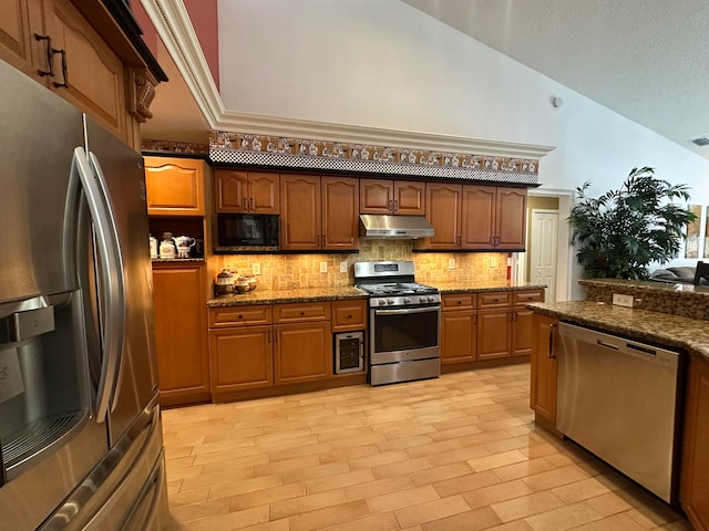 kitchen with tasteful backsplash, dark stone counters, vaulted ceiling, and appliances with stainless steel finishes