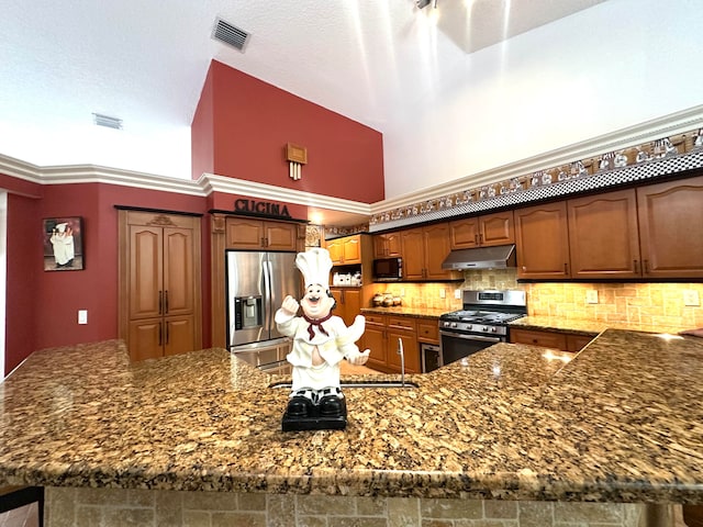 kitchen featuring stainless steel appliances, a high ceiling, dark stone countertops, decorative backsplash, and ornamental molding