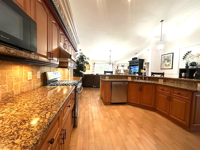 kitchen featuring pendant lighting, vaulted ceiling, light wood-type flooring, range hood, and stainless steel appliances