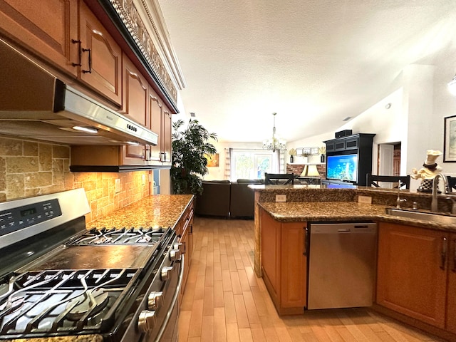 kitchen with sink, stainless steel appliances, light hardwood / wood-style flooring, a notable chandelier, and vaulted ceiling