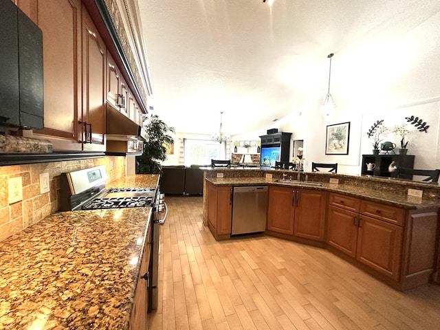 17976 88th Rd N, Loxahatchee, FL 33470 - kitchen with appliances with stainless steel finishes, a fireplace, open floor plan, light wood finished floors, and tasteful backsplash