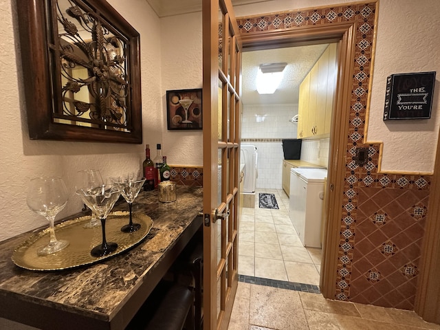 17976 88th Rd N, Loxahatchee, FL 33470 - bathroom featuring washing machine and clothes dryer, a textured wall, vanity, tile patterned flooring, and tile walls