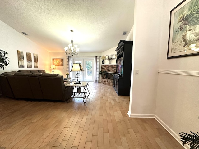 17976 88th Rd N, Loxahatchee, FL 33470 - living area with a chandelier, light wood-style flooring, baseboards, a fireplace, and a textured ceiling