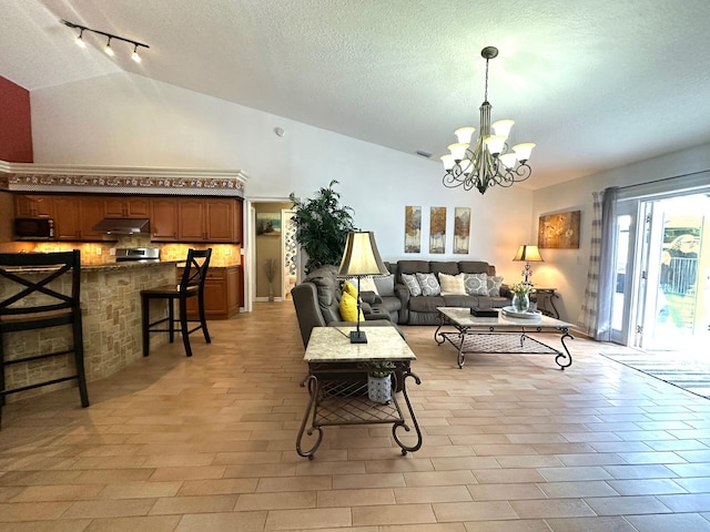 living room featuring a chandelier, a textured ceiling, track lighting, and high vaulted ceiling