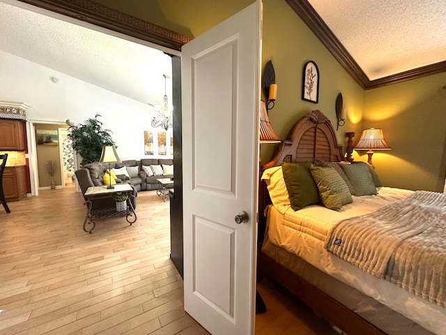 bedroom with vaulted ceiling, ornamental molding, a textured ceiling, and light wood-type flooring