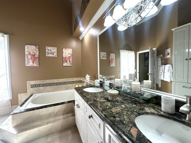 bathroom featuring tile patterned flooring, a relaxing tiled tub, and vanity