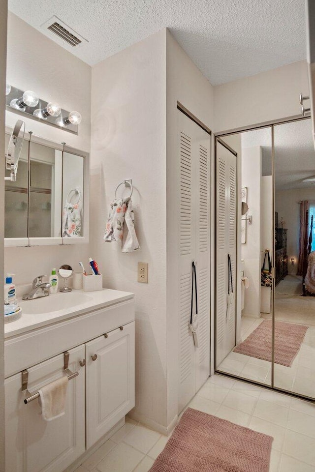 bathroom with tile patterned flooring, vanity, and a textured ceiling