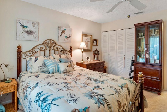 bedroom featuring a textured ceiling, a closet, light colored carpet, and ceiling fan