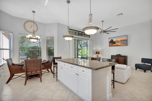 kitchen featuring plenty of natural light, a center island, dark stone countertops, and white cabinetry